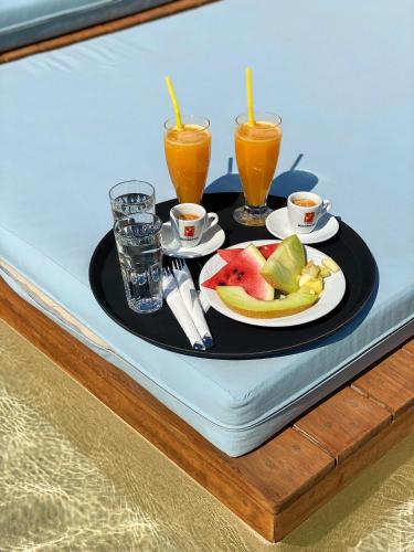 a tray with a plate of fruit and two glasses of orange juice at Argo Boutique Hotel in Naxos Chora
