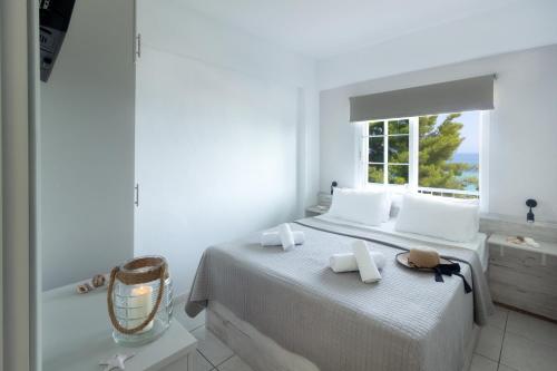 a white bedroom with a large bed with a window at Roditsa Patritsia Apartments in Polychrono