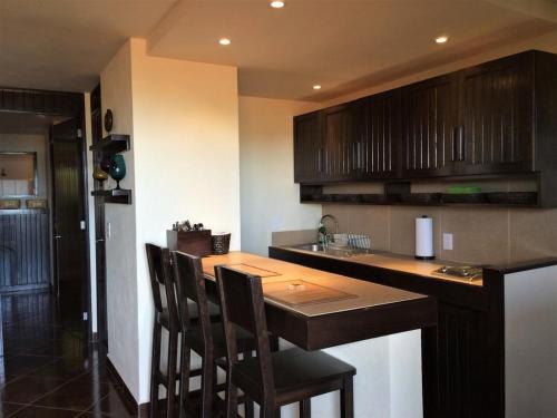 a kitchen with a bar with chairs and a counter top at Vista de las Rocas in Ixtapa