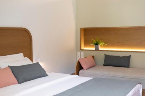 a bedroom with two beds and a plant on the wall at Mandraki Village Boutique Hotel in Koukounaries