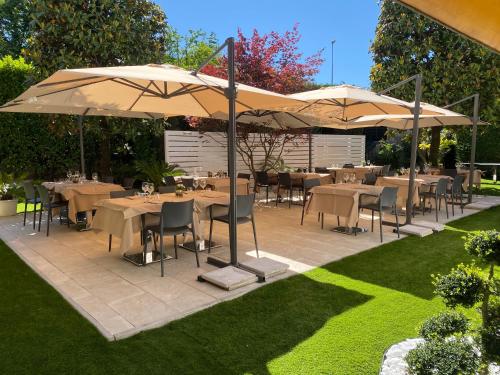 a patio with tables and umbrellas in a garden at Antica Locanda Del Villoresi in Nerviano