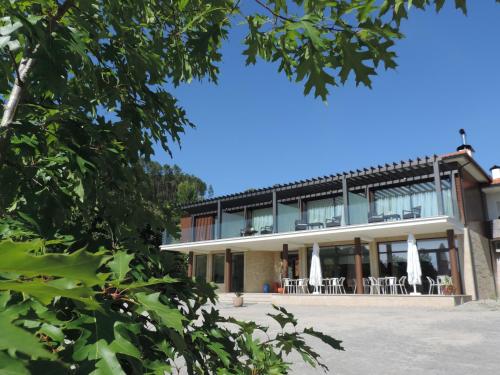 a building with chairs and umbrellas in front of it at Olhares do Lobo in Ponte da Barca