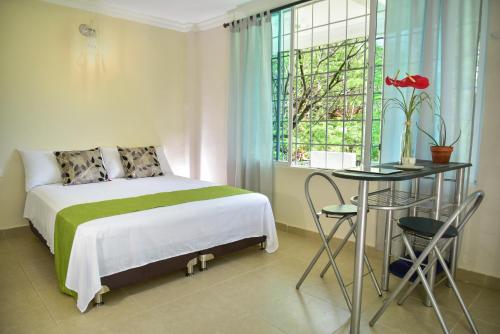 a bedroom with a bed and a table and a window at Perth House Taganga in Taganga