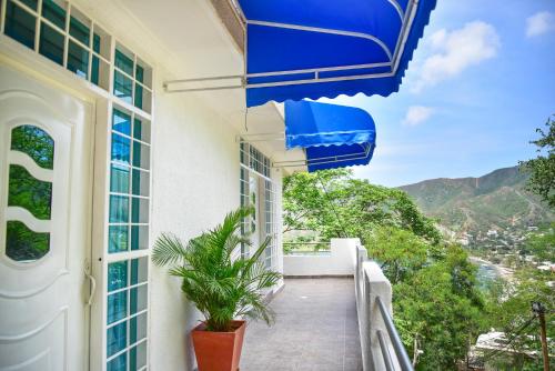 a balcony with a blue umbrella and a plant at Perth House Taganga in Taganga