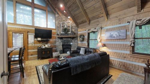 a living room with a leather couch and a fireplace at Blessed Nest Cabin in Townsend