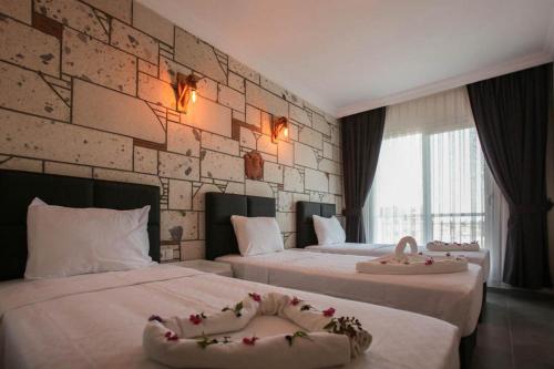una habitación de hotel con 2 camas con flores. en Lebedos Apart Hotel en Gumuldur