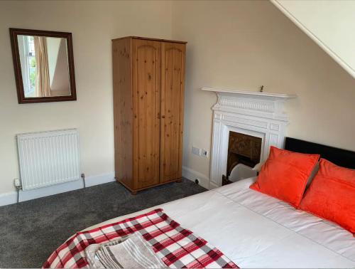 ein Schlafzimmer mit einem Bett mit roten Kissen und einem Kamin in der Unterkunft Grangemouth Apartments in Falkirk
