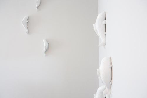 a group of torn paper on a white wall at Likio Studios in Batsi