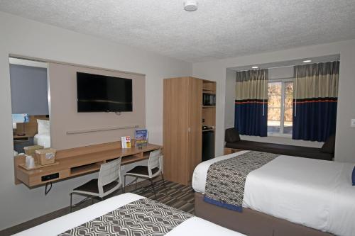 a hotel room with two beds and a desk at Microtel Inn by Wyndham Greensboro in Greensboro