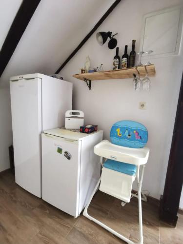 a small kitchen with a white refrigerator and a stool at Planinski kutak in Lovinac