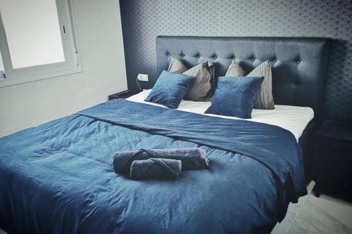 uma cama grande com lençóis azuis e almofadas azuis em Black Sun. Modern penthouse in Torrevieja em Torrevieja