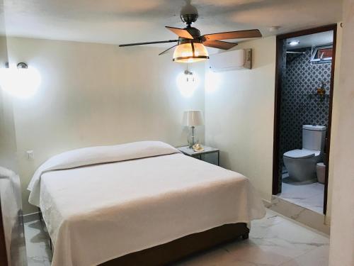 1 dormitorio con 1 cama y ventilador de techo en Hosteleria Casa Margarita, en Mazatlán