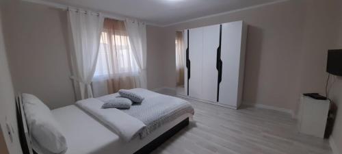 a white bedroom with a bed and a mirror at Casă de vacanță in Izvoare