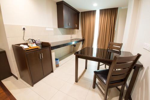 a kitchen with a table and chairs in a room at Lazenda Hotel in Labuan