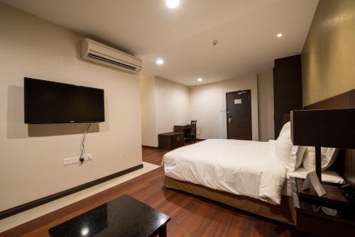 a hotel room with a bed and a flat screen tv at Lazenda Hotel in Labuan