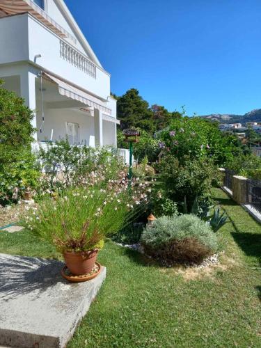 a garden with flowers and plants in front of a house at Apartman Katica in Rab