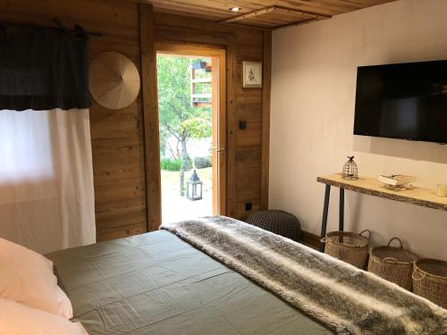 a bedroom with a bed and a flat screen tv at Le Pika in Hauteluce