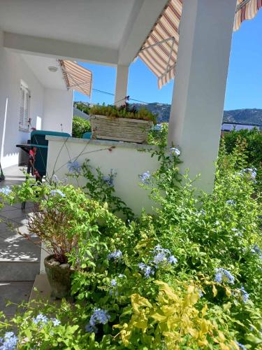 a porch with flowers and a planter on it at Apartman Katica in Rab
