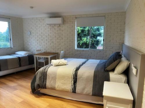 a bedroom with two beds and two windows at Bay House Motel in Bateau Bay
