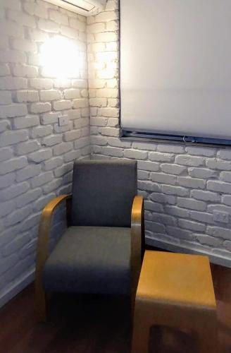 a chair and a bench in a room with a brick wall at Bay House Motel in Bateau Bay