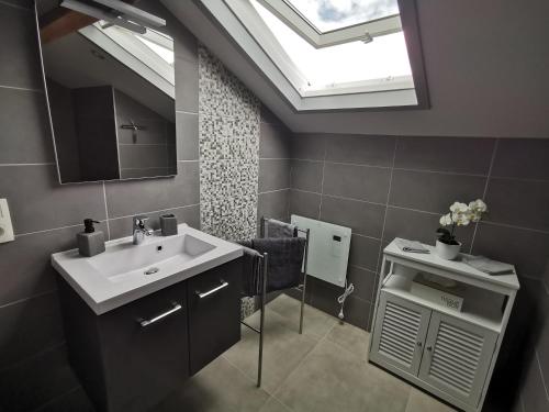 a bathroom with a sink and a mirror and a skylight at Les Suites de Meiz in Stavelot