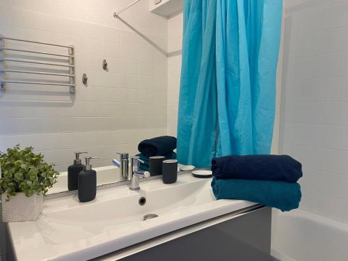 a bathroom with a sink and a blue shower curtain at T2 Vue exceptionnelle sur le bassin d'Arcachon in Andernos-les-Bains