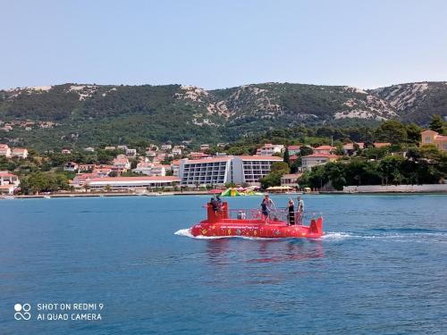 a red boat in the water with people on it at Apartman Katica in Rab