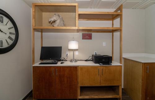 Habitación con escritorio, ordenador portátil y reloj. en Equus Inn I75 en Ocala
