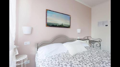 a white bedroom with a bed and a picture on the wall at La Linea D'Acqua in Manarola