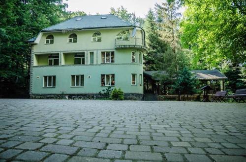 a large white house with a large brick driveway at База відпочинку ШИПОВЕЦЬ in Poroškov
