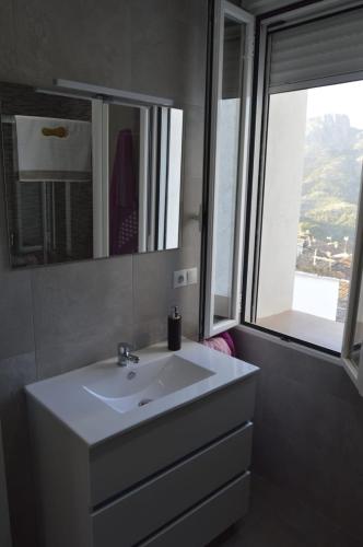 a bathroom with a white sink and a window at CASA CARAVINA in Benimantell