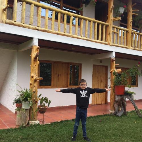 a young boy standing in front of a house at CABAÑA LOS NOGALES in San Agustín