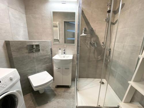 a bathroom with a shower and a toilet and a sink at Kosmo Apartament in Wrocław