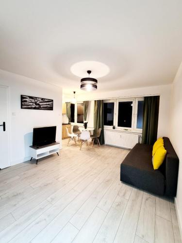 a living room with a couch and a television at Apartament Parkowy Mrągowo in Mrągowo