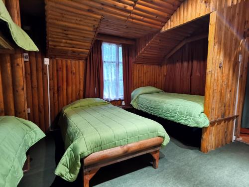 a bedroom with two beds in a wooden cabin at Salto del Indio - Cabañas Lemunantu in Manzanar
