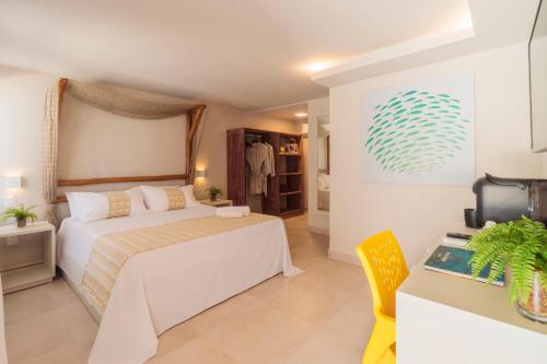 a bedroom with a large white bed and a tv at Pousada Tabajuba in Porto De Galinhas