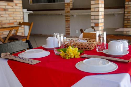 einem roten und weißen Tisch mit Tellern und Gläsern darauf in der Unterkunft Pousada Kairos & Spa em Búzios in Búzios