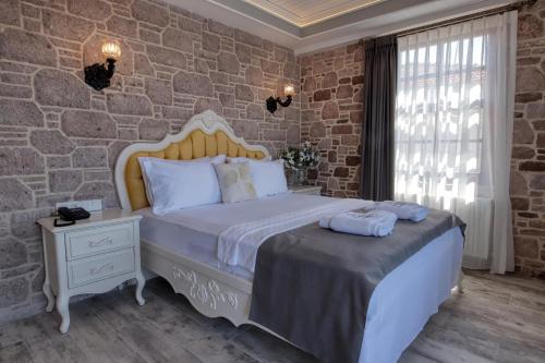 a bedroom with a large bed and a stone wall at Cunda Taka in Ayvalık