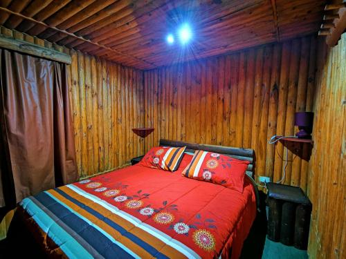Un dormitorio con una cama en una pared de madera. en Salto del Indio - Cabañas Lemunantu, en Manzanar
