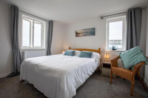 a bedroom with a large white bed and two windows at OA Surf Club in Bude