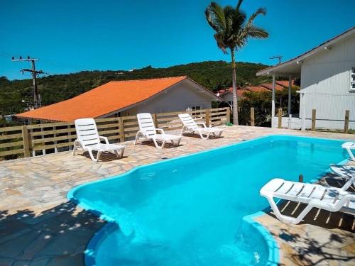 una piscina con sillas y una palmera en Pousada Essência do Rosa, en Praia do Rosa