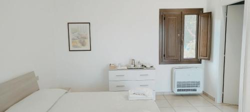 Habitación blanca con cama y lavamanos en Sa Teria Village - Camere Deluxe - en Tertenìa