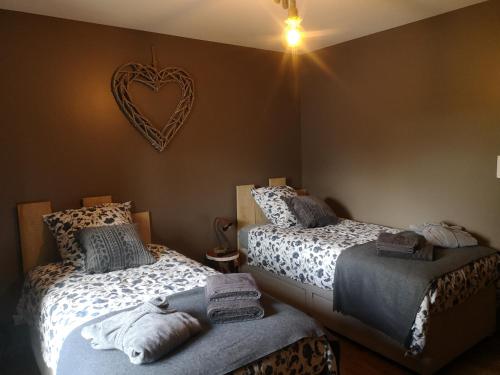 a bedroom with two beds and a heart sign on the wall at Gîte La Grange de La Trigalle avec spa professionnel privatif in Valognes