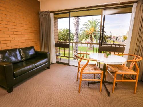 a living room with a couch and a table and chairs at Mildura River City Motel in Mildura