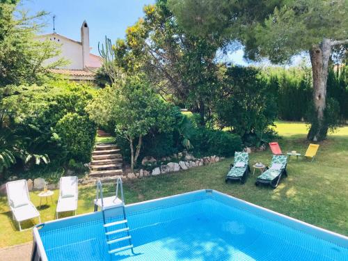 a backyard with a swimming pool and a yard with chairs at Casa mediterránea con gran jardín y piscina a 500 m de la playa in Roda de Bará
