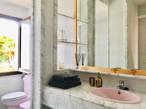 a bathroom with a sink and a toilet and a mirror at Casa mediterránea con gran jardín y piscina a 500 m de la playa in Roda de Bará