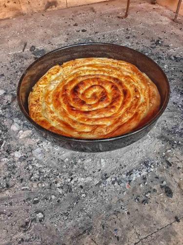 a pie in a pan on the ground at Apartmani Vila na Drini in Foča