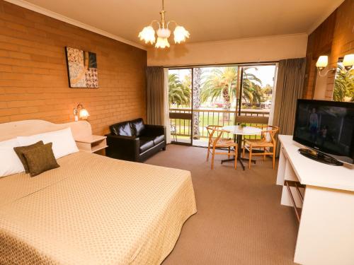 a hotel room with a bed and a television and a table at Mildura River City Motel in Mildura