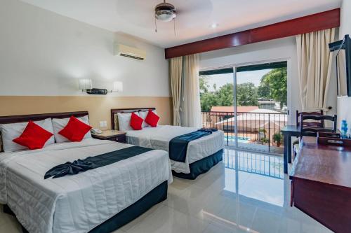 two beds in a hotel room with a balcony at Hotel Siglo 21 Merida in Mérida