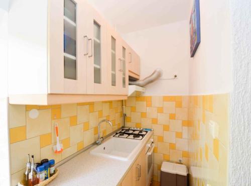 una cocina con azulejos amarillos y blancos en la pared en Pula Apartment 11 en Veruda